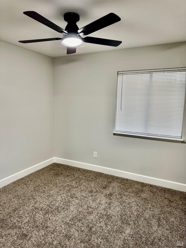 carpeted spare room featuring ceiling fan and baseboards