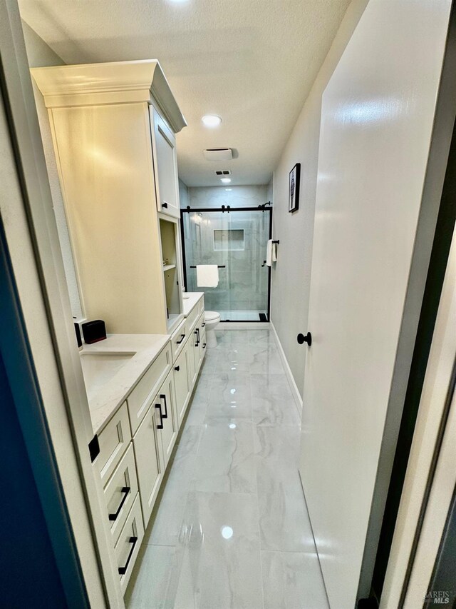 full bathroom with a shower stall, vanity, marble finish floor, baseboards, and toilet