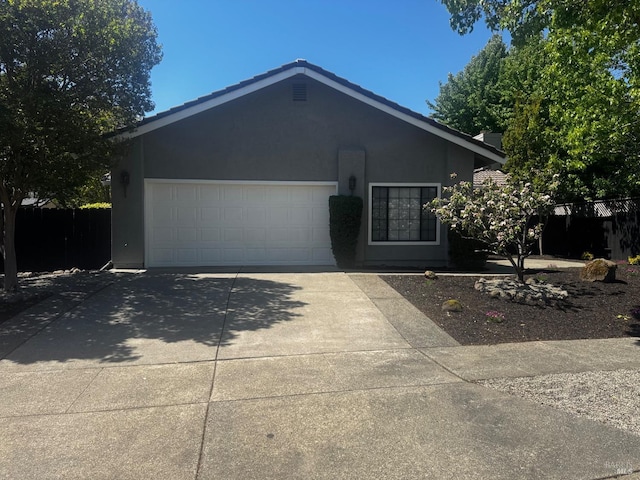 ranch-style house featuring an attached garage, driveway, fence, and stucco siding