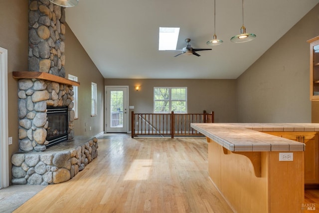 16589 Glenda Dr, Guerneville, CA 95446 - kitchen with tile counters, a ceiling fan, a fireplace, light wood-type flooring, and a skylight