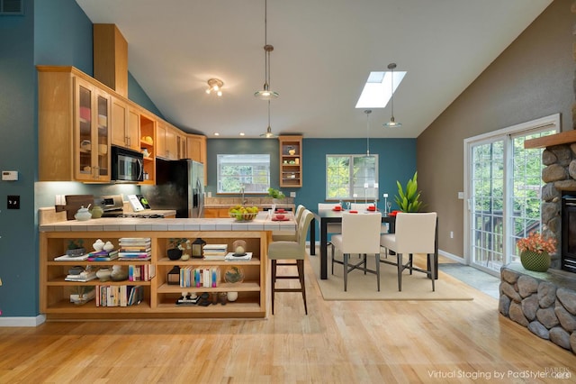 16589 Glenda Dr, Guerneville, CA 95446 - kitchen featuring stainless steel appliances, open shelves, light wood finished floors, a skylight, and high vaulted ceiling