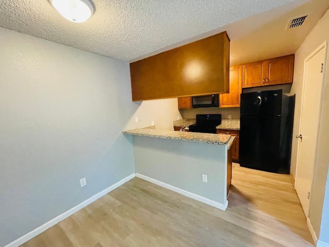 kitchen featuring a textured ceiling, black appliances, brown cabinets, light countertops, and visible vents