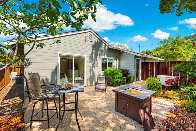 back of house featuring a fenced backyard, a patio area, and an outdoor fire pit