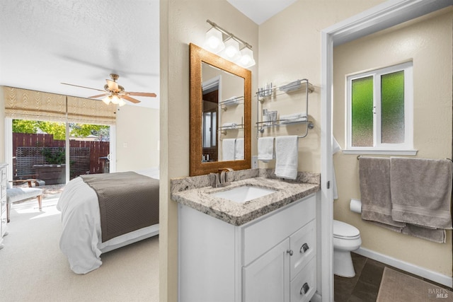 bathroom with baseboards, toilet, vanity, and ceiling fan