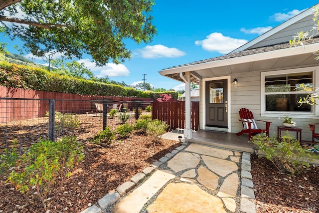 doorway to property with fence and covered porch
