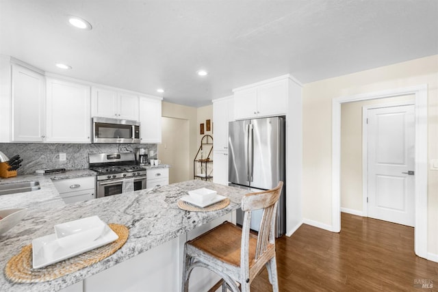 kitchen with stainless steel appliances, baseboards, white cabinets, a peninsula, and dark wood-style floors