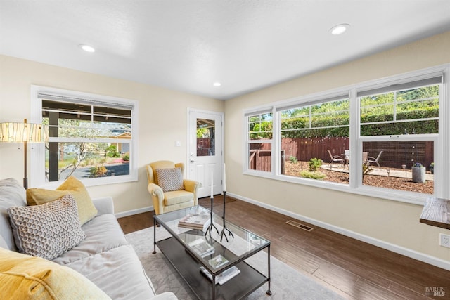 living area with recessed lighting, wood finished floors, visible vents, and baseboards