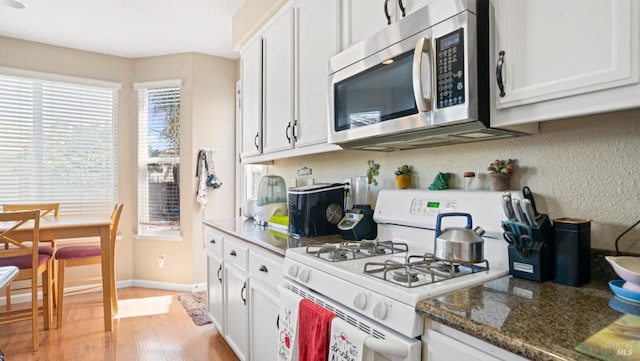 1220 Bello Dr, Dixon, CA 95620 - kitchen with white cabinets, white gas range oven, light wood-style floors, and stainless steel microwave