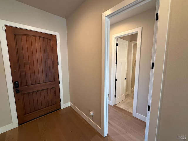 hallway featuring baseboards, recessed lighting, arched walkways, and wood finished floors