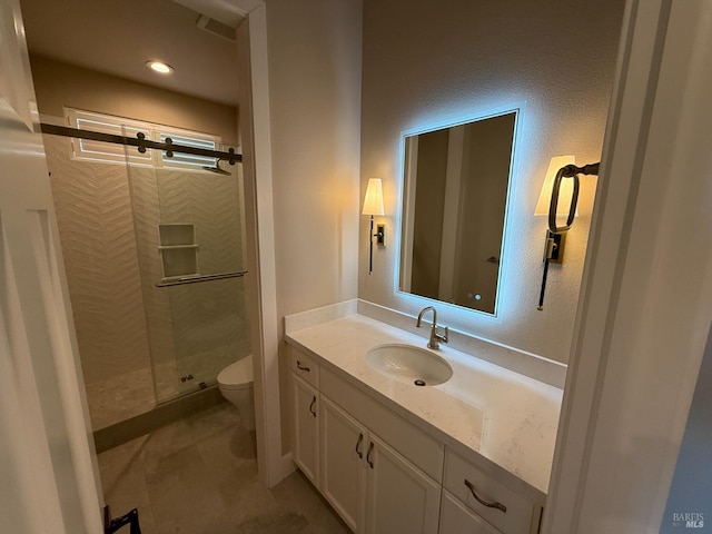 bathroom featuring a stall shower, toilet, a textured wall, and vanity