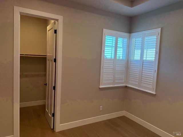 unfurnished bedroom featuring a closet, wood finished floors, and baseboards