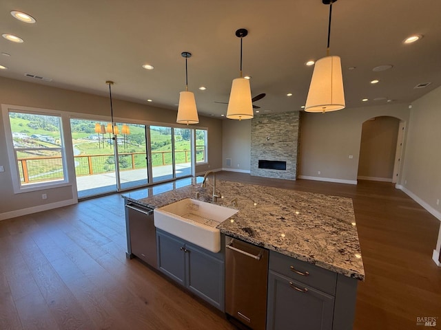 kitchen with a sink, dark wood-style floors, baseboards, open floor plan, and dishwasher
