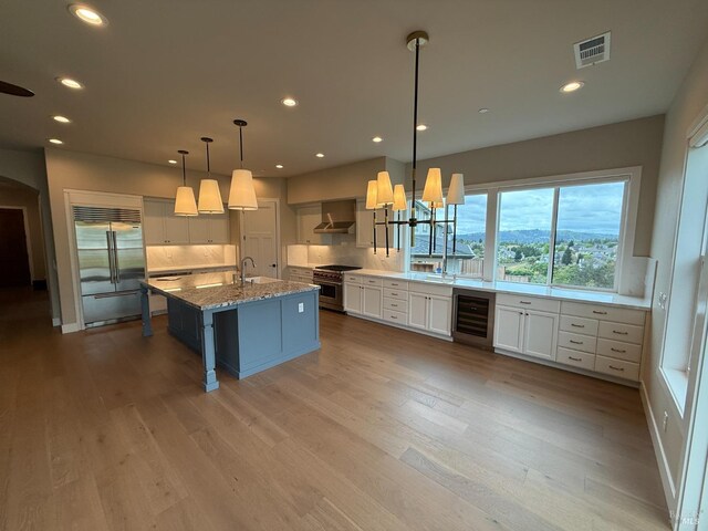 kitchen featuring decorative backsplash, visible vents, light stone countertops, wine cooler, and high end appliances