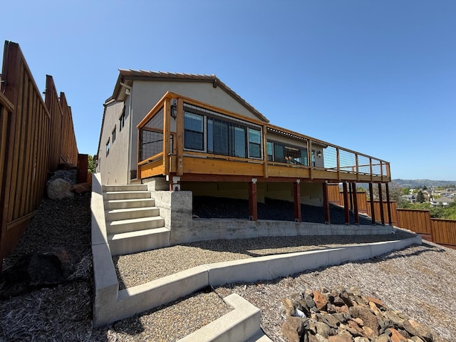 back of house featuring a wooden deck, stucco siding, and fence