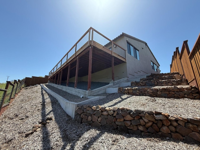 back of property featuring fence, a deck, and stucco siding