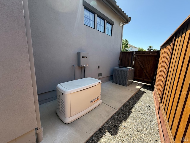 view of property exterior with a gate, a patio area, stucco siding, fence, and central AC