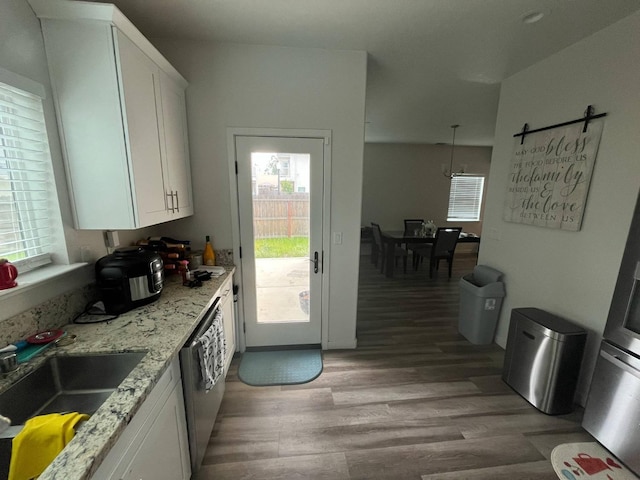 kitchen featuring plenty of natural light, a sink, light wood finished floors, and white cabinets