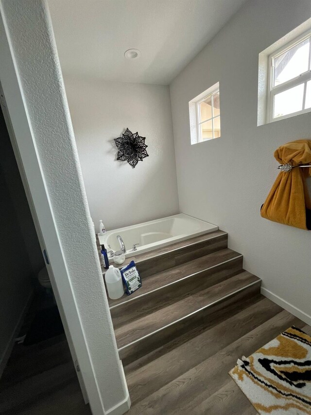 stairway with baseboards, plenty of natural light, and wood finished floors