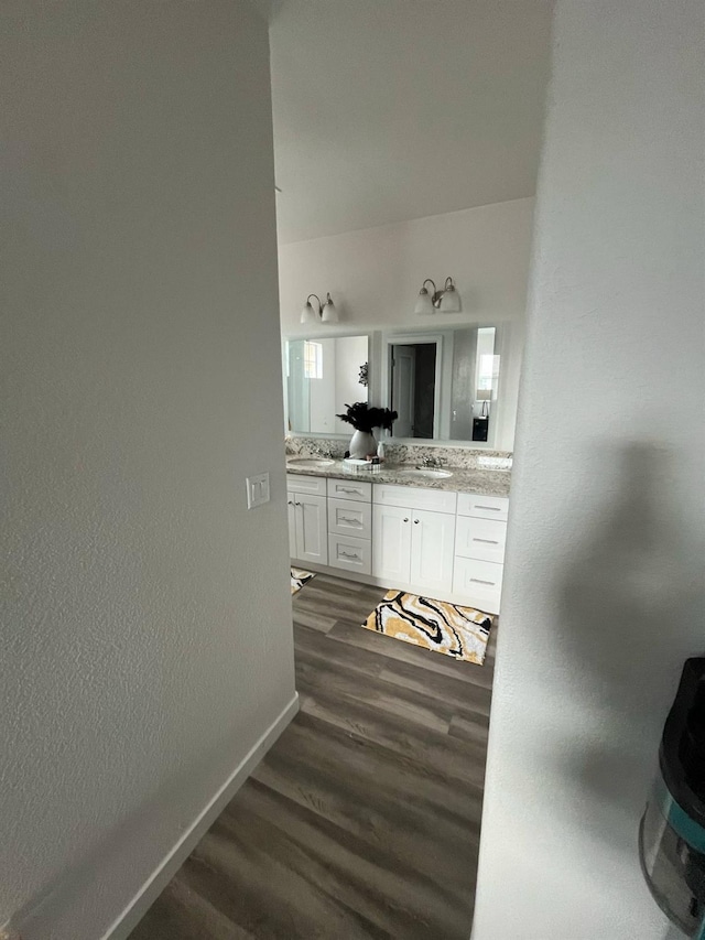 bathroom featuring double vanity, a sink, baseboards, and wood finished floors