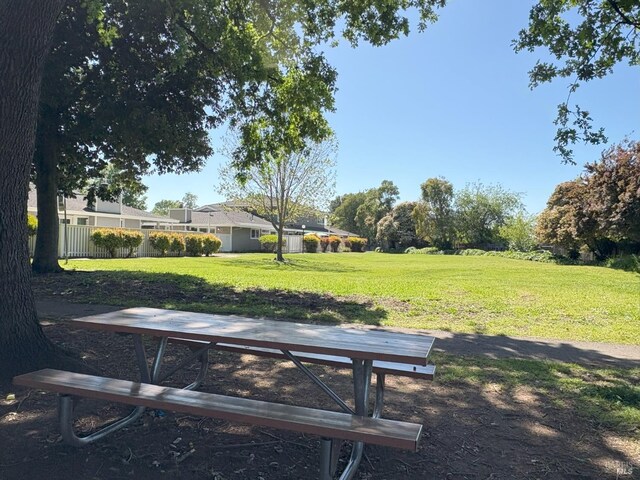 surrounding community with fence and a yard