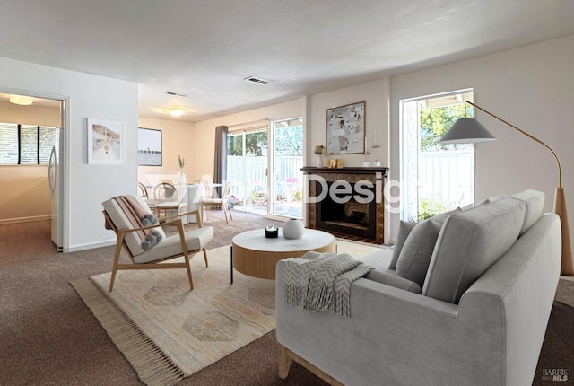 living room featuring plenty of natural light, a fireplace, baseboards, and carpet