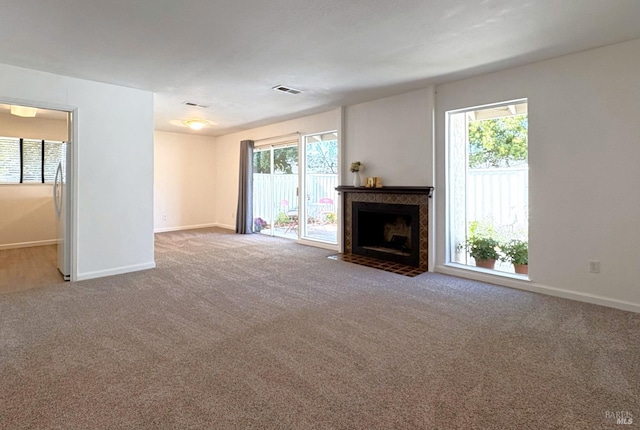 unfurnished living room featuring baseboards, carpet flooring, and a healthy amount of sunlight