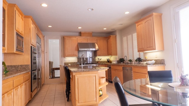 kitchen featuring recessed lighting, an island with sink, light brown cabinets, and under cabinet range hood