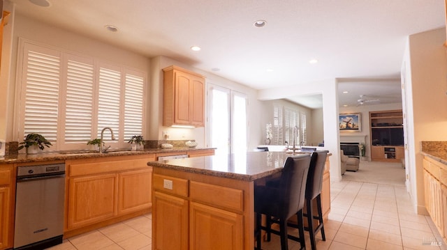 kitchen with a kitchen island, a wealth of natural light, light tile patterned floors, and a sink