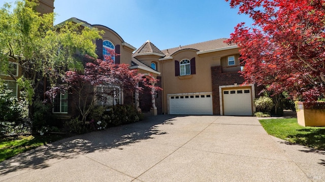 view of front of property with an attached garage, a tiled roof, stucco siding, and concrete driveway