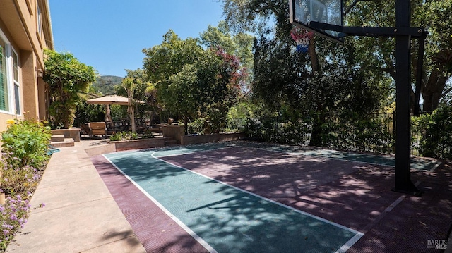 view of sport court featuring basketball hoop and fence