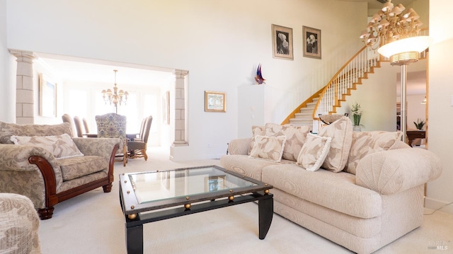 carpeted living room featuring an inviting chandelier, stairs, and decorative columns