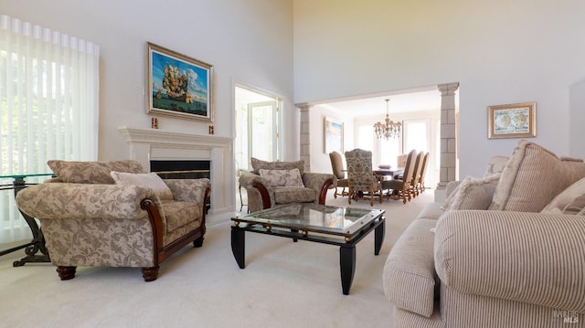 living room with light colored carpet, a towering ceiling, a chandelier, and ornate columns
