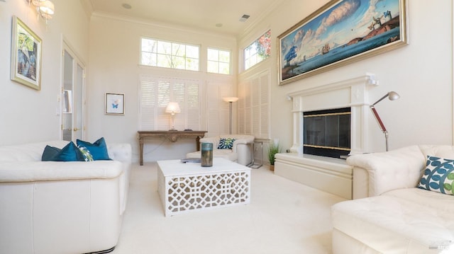 carpeted living area featuring a high ceiling, crown molding, a glass covered fireplace, and visible vents