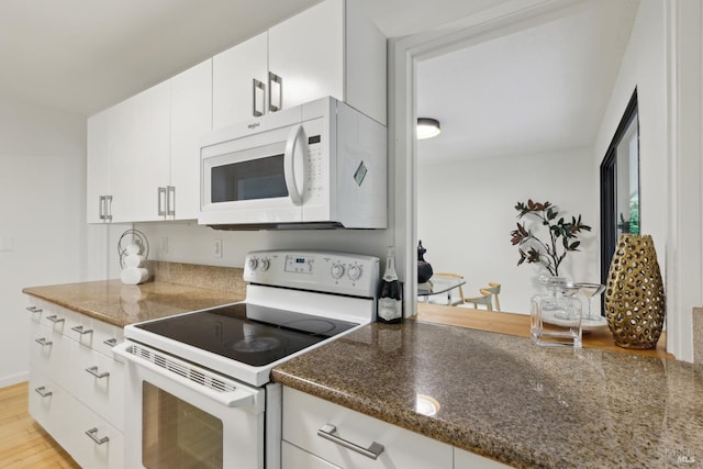 kitchen featuring light wood-type flooring, dark stone countertops, white appliances, and white cabinetry