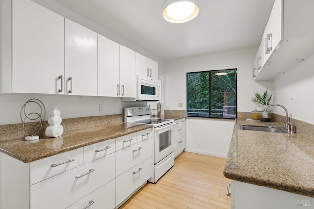 kitchen featuring stone countertops, a sink, white appliances, light wood-style floors, and white cabinetry