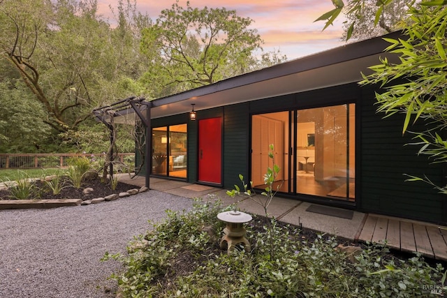 back of property at dusk featuring fence