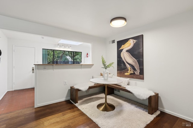 sitting room with wood finished floors, visible vents, and baseboards