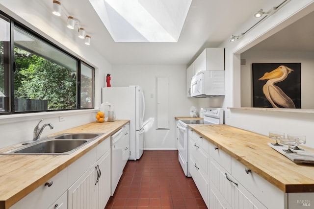 kitchen featuring a skylight, butcher block counters, white appliances, and a sink