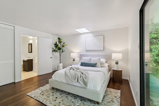 bedroom with a skylight, baseboards, connected bathroom, and dark wood-style flooring