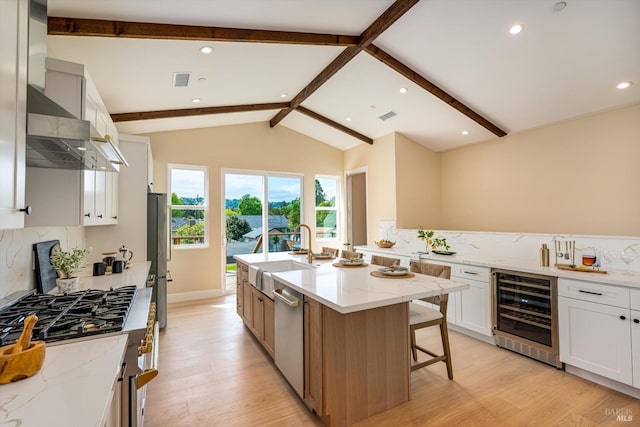 kitchen with light wood-style flooring, appliances with stainless steel finishes, wine cooler, and a sink