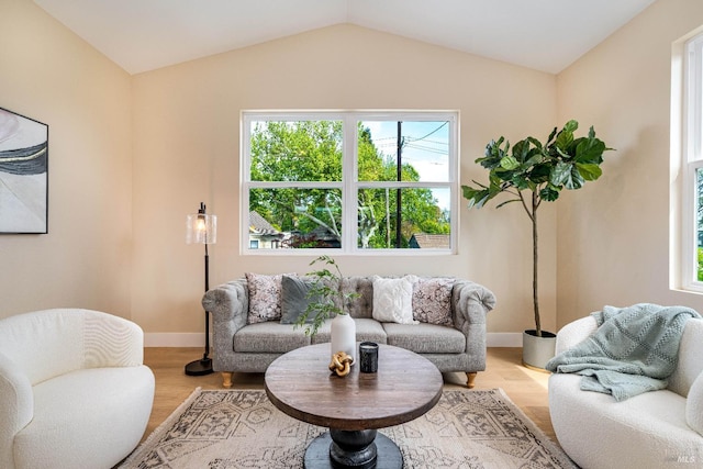 living area with vaulted ceiling, wood finished floors, and baseboards