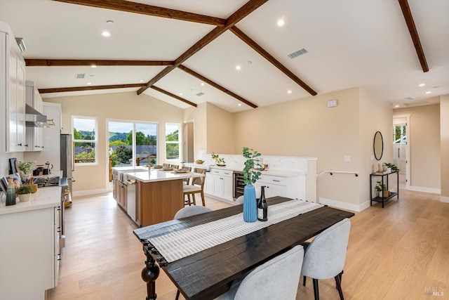 dining space featuring lofted ceiling with beams, light wood-type flooring, visible vents, recessed lighting, and beverage cooler