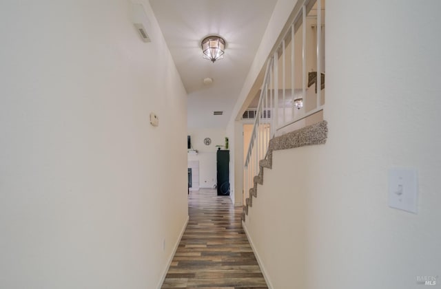 corridor with baseboards, stairs, and dark wood-style floors