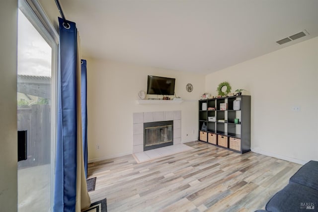 living area with wood finished floors, a tile fireplace, and visible vents
