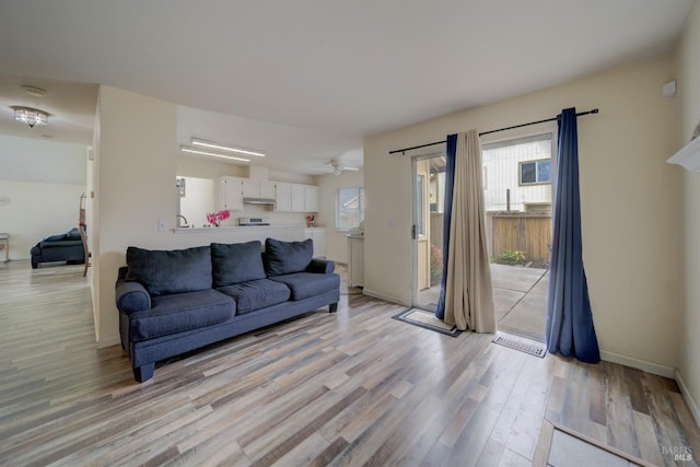 living area with light wood finished floors, baseboards, and ceiling fan