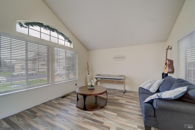 living room with high vaulted ceiling, baseboards, wood finished floors, and visible vents