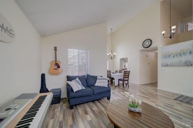 living room featuring baseboards, wood finished floors, an inviting chandelier, and high vaulted ceiling