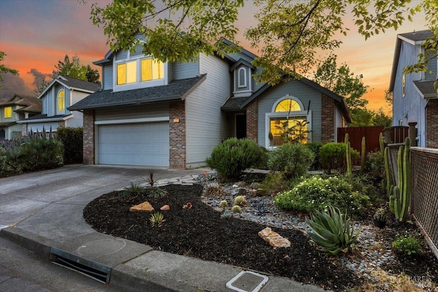 traditional-style house featuring brick siding, an attached garage, concrete driveway, and fence