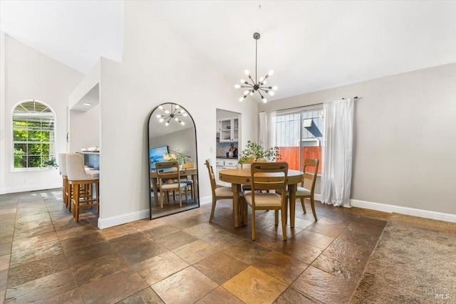 dining area with stone tile floors, baseboards, a notable chandelier, and a healthy amount of sunlight
