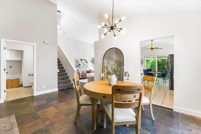 dining area with baseboards, stone tile flooring, high vaulted ceiling, and stairs